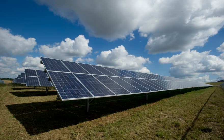 Parque solar en un campo bajo cielo con nubes